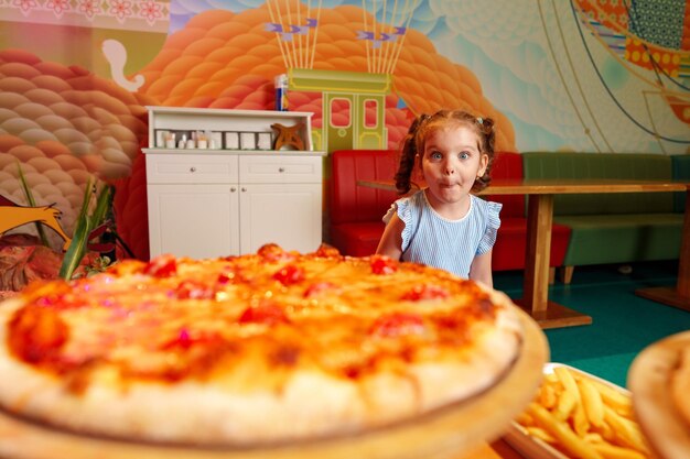 Foto ein kleines mädchen sitzt vor einer pizza