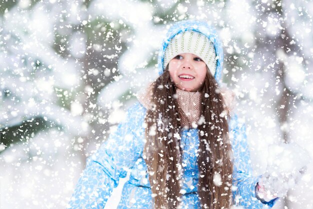 Ein kleines Mädchen spielt mit Schneebällen in einem Wald