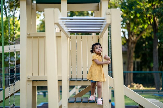 Ein kleines Mädchen steht auf einem Spielplatz mit Rutsche und grüner Rutsche.