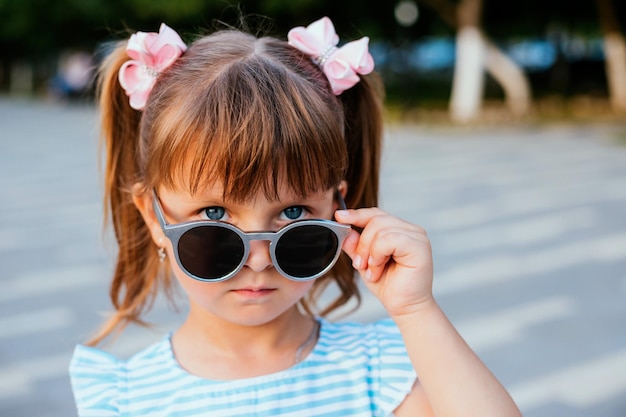 Ein kleines Mädchen steht in einer Sonnenbrille Schutz vor Sonnenlicht Unterhaltung und Verwöhnung des Kindes