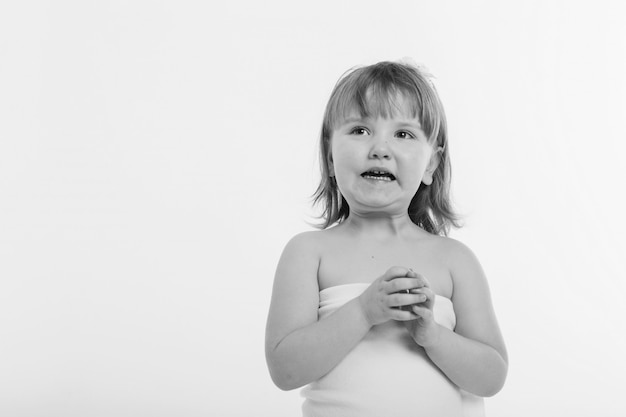 Ein kleines Mädchen verzieht das Gesicht vor einem weißen Hintergrund.