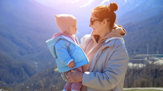 Ein kleines Mädchen will eine Sonnenbrille für seine Mutter tragen, um sich gegen die Berge zu wehren.