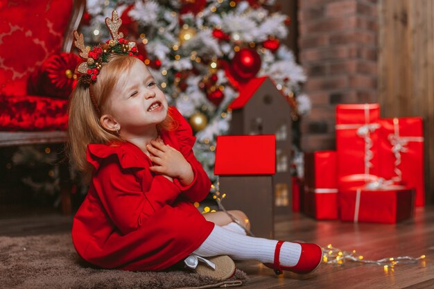 ein kleines Mädchen wünscht sich unter einem Weihnachtsbaum