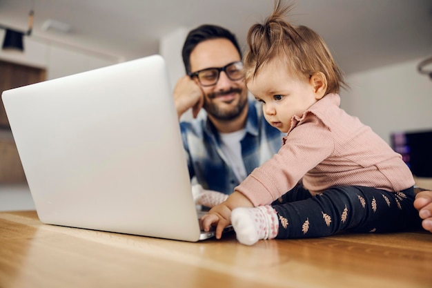 Ein kleines Mädchen zeigt ihrem Vater, wie die Arbeit auf einem Laptop erledigt wird