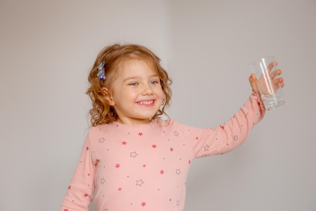 Ein kleines Mädchen zu Hause hält ein Glas Wasser empfiehlt