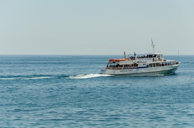 Ein kleines Motorschiff fährt an einem Sommertag Menschen auf dem Meer.