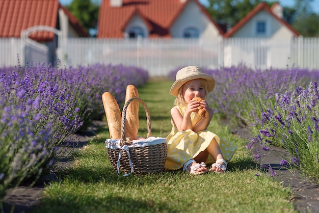 Ein kleines schönes Mädchen, das auf einem Feld des Lavendels isst.