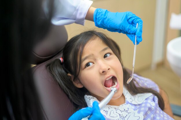 Ein kleines süßes Mädchen, das die Zähne vom Zahnarzt in der Zahnklinik untersuchen lässt