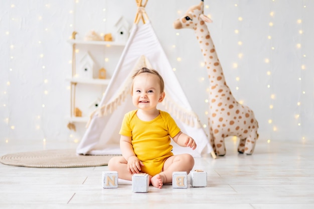 Ein kleines süßes Mädchen sitzt in einem hellen, gemütlichen Kinderspielzimmer Textilien für Kinder