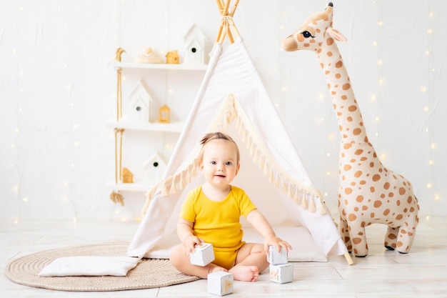 Ein kleines süßes Mädchen sitzt in einem hellen, gemütlichen Kinderspielzimmer Textilien für Kinder