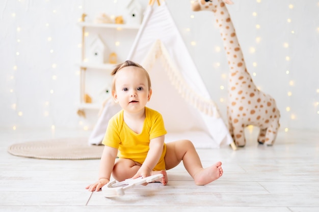 Ein kleines süßes Mädchen sitzt in einem hellen, gemütlichen Kinderspielzimmer Textilien für Kinder