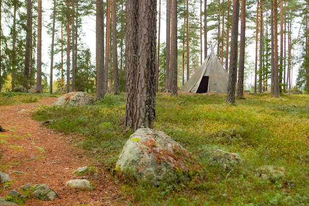 Ein kleines Tipi steht im Wald mit einem großen Felsen im Vordergrund.