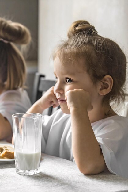 Ein kleines trauriges Vorschulmädchen sitzt beim Frühstück am Tisch und will nicht essen