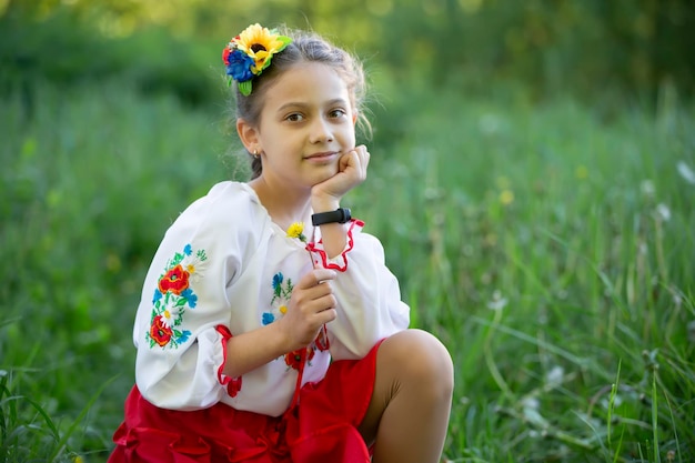 Ein kleines ukrainisches und belarussisches Mädchen in einem bestickten Hemd auf sommerlichem Hintergrund