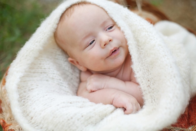 Ein kleines zwei Monate altes Baby liegt auf dem Bauch und hat den Kopf in eine weiche, weiße, flauschige Decke gewickelt. Hochwertiges Foto