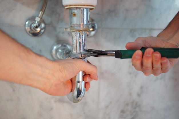Ein Klempner repariert die Rohre eines Waschbecken
