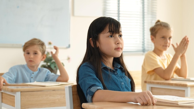 Ein kluger Grundschüler schaut auf den Lehrer, während er in der Klassenzimmerpädagogik ist