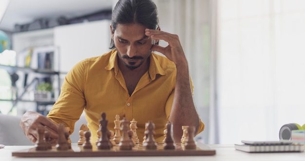 Ein kluger Mann spielt zu Hause Schach. Er bewegt Figuren auf dem Schachbrett und denkt an das Konzept von Strategiespielen.