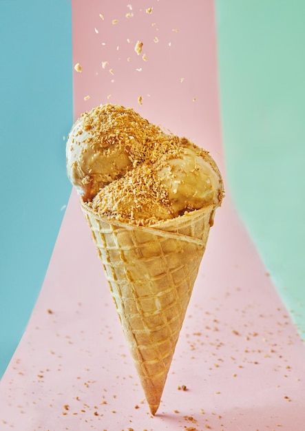 Ein köstlicher Eiscreme-Kegel mit Nüssen, die auf einem mehrfarbigen Hintergrund isoliert sind
