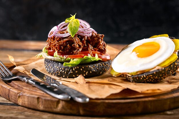 Ein köstlicher, heißer, würziger schwarzer Burger mit Chili-Pfeffer und einem Glas Bier auf einem Schneidbrett auf weißem Holz