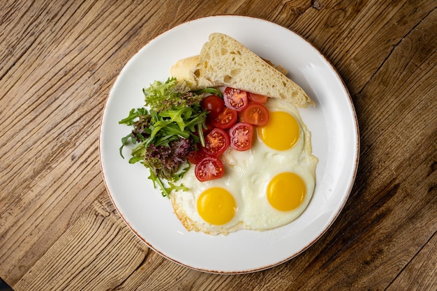 ein köstliches Frühstück auf einem im Restaurant zubereiteten Teller. Spiegeleier mit Tomaten und Salat