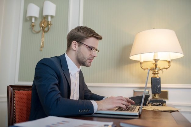 Ein konzentrierter Geschäftsmann, der eine Brille trägt und wichtige Arbeit leistet