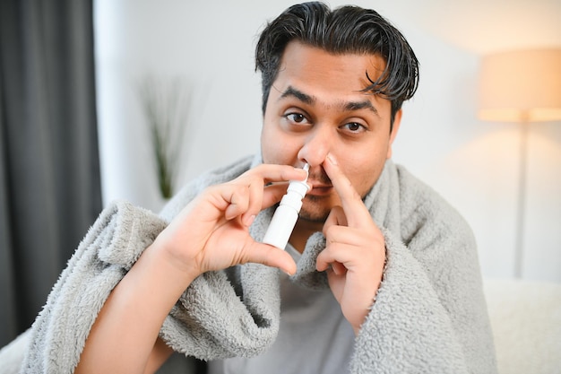 Ein kranker Indianer wird zu Hause behandelt und verwendet ein Nasenspray Gesundheitskonzept