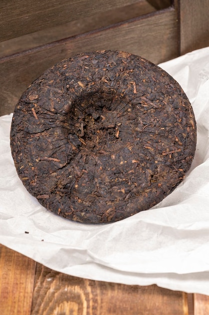 Ein Kreis aus komprimiertem chinesischem schwarzem Puerh-Tee auf Holzhintergrund