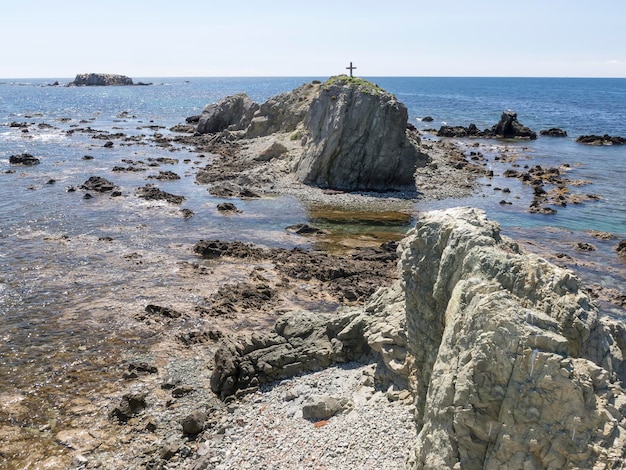 Ein Kreuz auf einem Felsen vor dem Meer