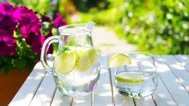 Ein Krug Limonade und ein Glas auf einem Tisch im Garten