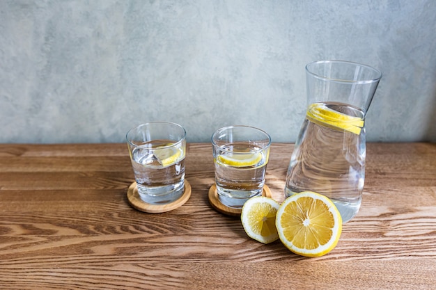 Ein Krug und Gläser reines Wasser mit Zitrone. Das Konzept eines gesunden Lebensstils