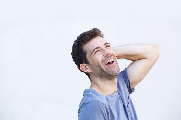 Ein lachender junger Mann mit den Händen in den Haaren vor weißem Hintergrund