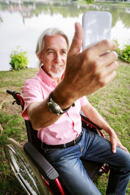 Foto ein lächelnder älterer mann fotografiert, während er im rollstuhl sitzt