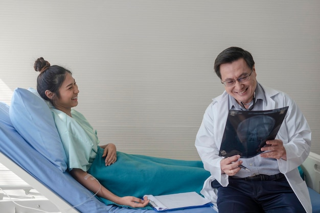 Ein lächelnder Arzt spricht mit einem Patienten, während er einen medizinischen Röntgenbild hält