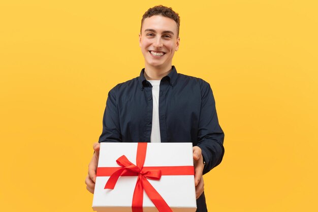 Ein lächelnder, cooler kaukasischer junger Mann schenkt ein Geschenk