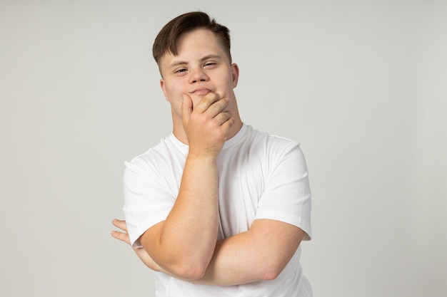 Ein lächelnder junger Mann mit zerebraler Lähmung in einer Brille und einem weißen T-Shirt posiert für die Kamera für das Konzept des Welttages der genetischen Krankheiten