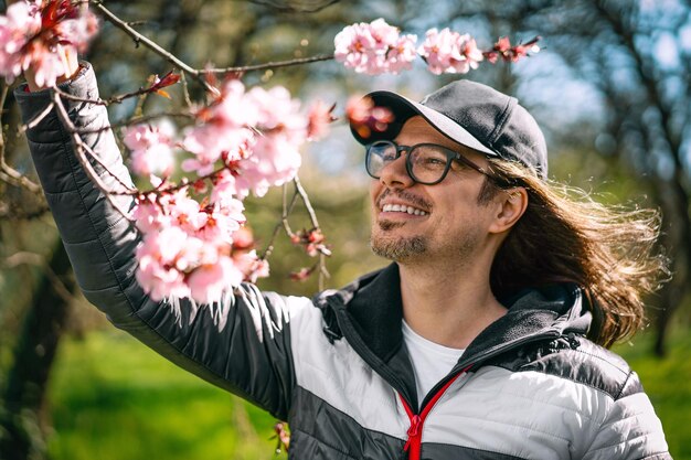 Foto ein lächelnder mann bei einem blühenden baum im frühling