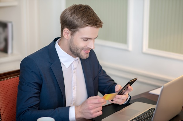 Ein lächelnder Mann, der mit einer App Geld überweist