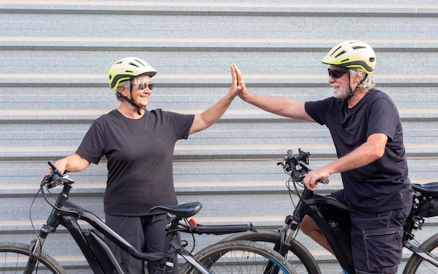 Ein lächelndes älteres Paar genießt sportliche Aktivitäten zusammen mit einem lustigen Ruhestandskonzept für Elektrofahrräder