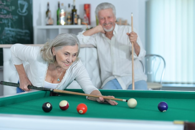 ein lächelndes älteres Paar spielt zusammen Billard