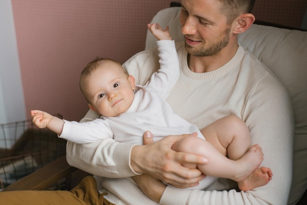 Ein lächelndes Baby in den Armen seines jungen, glücklichen Vaters