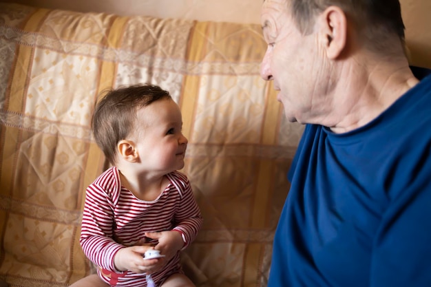 Ein lächelndes Baby und ihr Großvater spielen zusammen