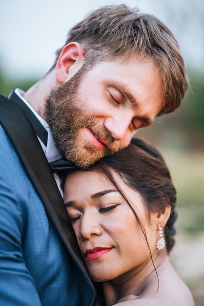 Foto ein lächelndes, frisch verheiratetes paar umarmt sich mit geschlossenen augen.