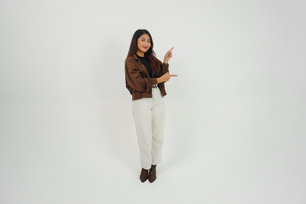 Ein lächelndes junges asiatisches Mädchen in brauner Jacke steht und weist auf einen Kopierplatz neben ihr hin