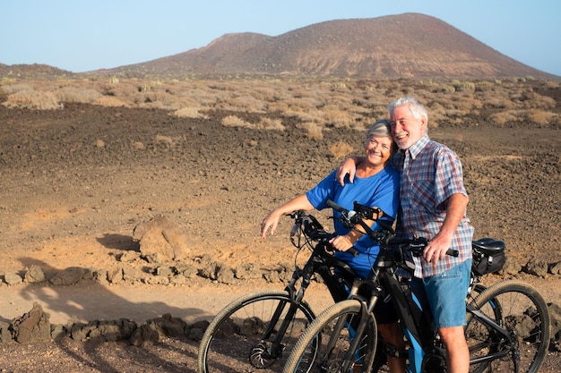 Ein lächelndes Paar fährt Fahrräder auf dem Feld gegen den Berg