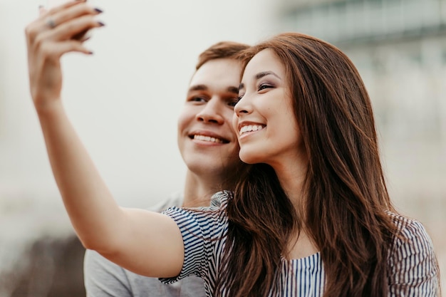Ein lächelndes Paar macht bei Sonnenuntergang ein Selfie in der Stadt