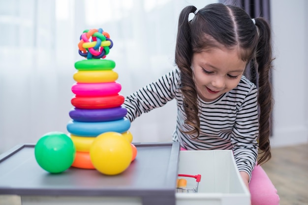 Ein lächelndes, süßes Mädchen, das zu Hause mit Spielzeug spielt