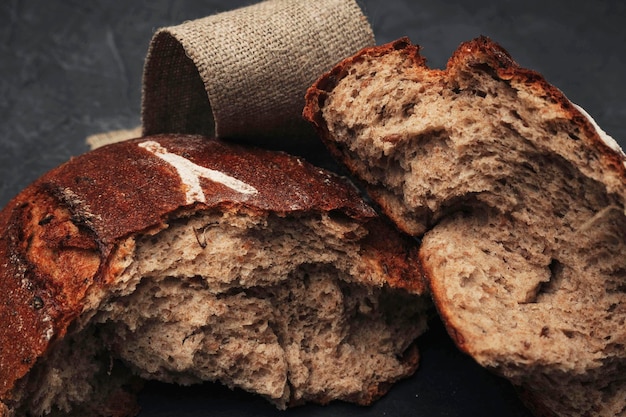 Ein Laib rundes warmes Brot in zwei Hälften gebrochen Frisch gebackenes dunkles Kornbrot