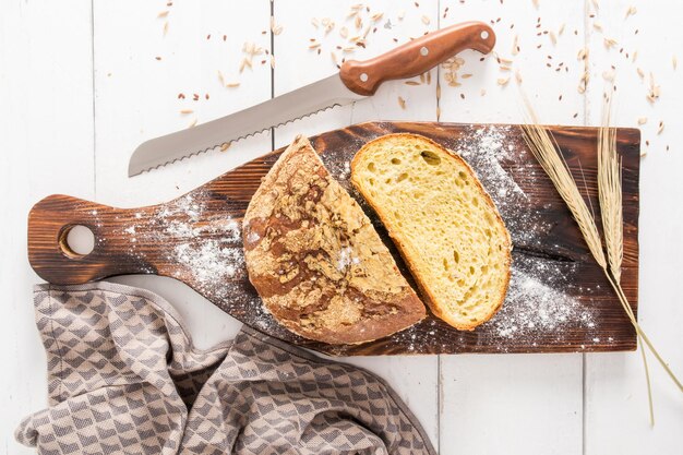 Ein Laib und ein geschnittenes Stück gebackenes Maisbrot auf einem hölzernen Küchenbrettmesser zum Schneiden von Draufsicht