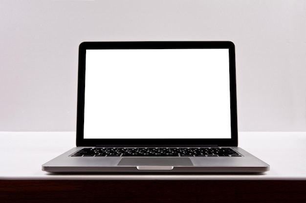 Ein Laptop mit weißem Bildschirm liegt aufgeschlagen auf einem Schreibtisch.